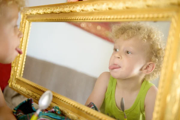 Un niño pequeño metiendo la lengua en el espejo —  Fotos de Stock