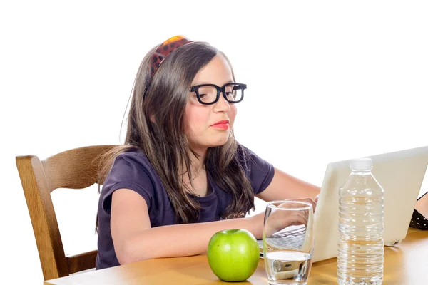 En lille pige gør sit hjemmearbejde på sin computer - Stock-foto