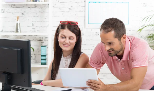 Een jonge uitvoerende macht en zijn secretaresse kijken naar een tablet — Stockfoto