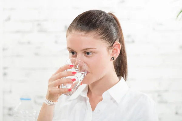 En ung kvinna dricka ett glas vatten — Stockfoto