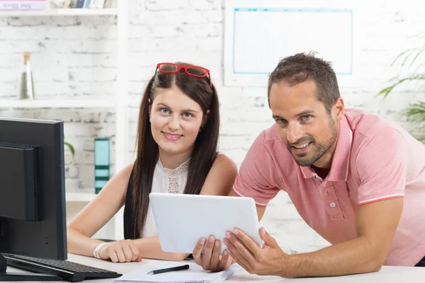 Een jonge uitvoerende macht en zijn secretaresse kijken naar een tablet — Stockfoto