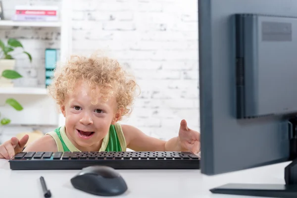 A little blond boy plays with a computer — Stock Photo, Image