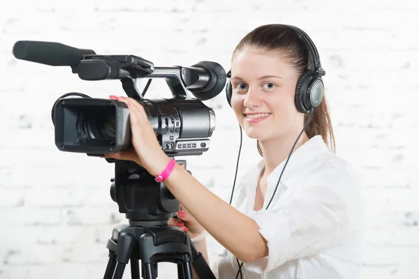 Eine hübsche junge Frau mit professioneller Kamera und Kopfhörer — Stockfoto