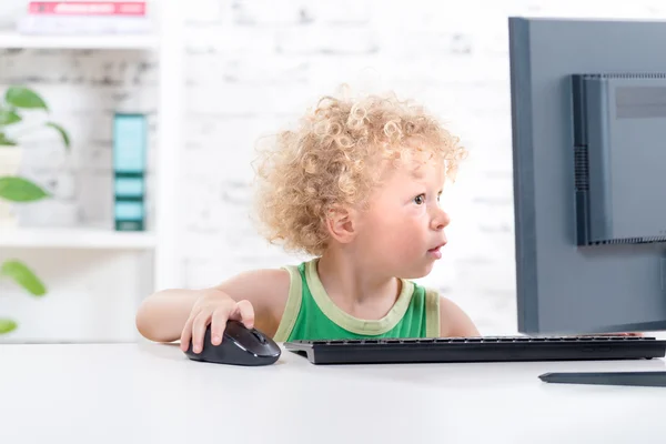 A little blond boy playing with the mouse of a computer — Stock Photo, Image