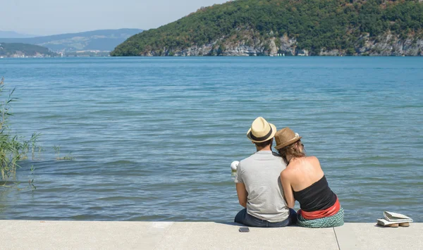 Amante casal, vista para trás, sentado perto da água — Fotografia de Stock