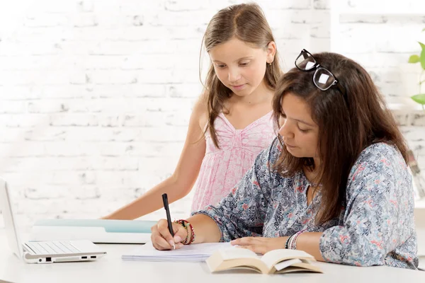 A teenage girl and her younger sister at his desk — Stock Fotó