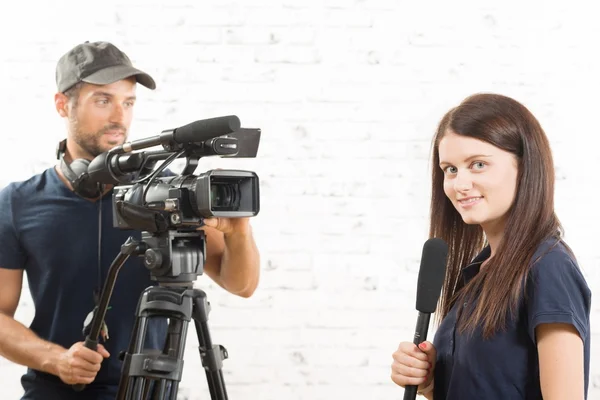 Una joven periodista con un micrófono y un camarógrafo — Foto de Stock