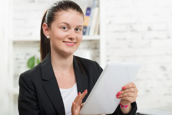 Een jonge vrouw met een zwarte jas kijken naar een tablet — Stockfoto