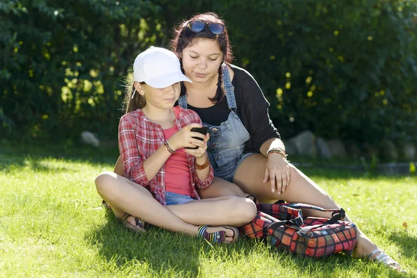Una hija y una hermana juegan con un teléfono — Foto de Stock