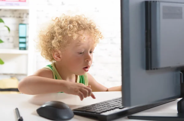 Een kleine blonde jongen spelen met het toetsenbord van een computer — Stockfoto