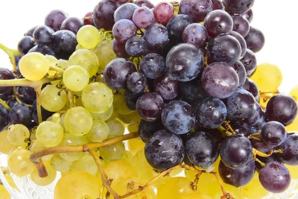 Uvas blancas y negras en un recipiente de vidrio aislado sobre blanco — Foto de Stock