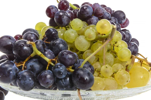 Uvas blancas y negras en un recipiente de vidrio aislado sobre blanco — Foto de Stock