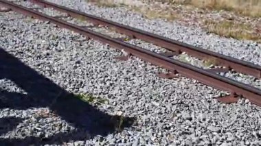 Yerde çakıl olan tren rayları. Yerde bir gölge var.