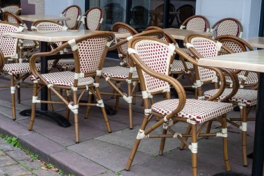 Bir restoranın önünde sıra sıra dizilmiş sandalyeler. Sandalyelerin hepsi boş. Arka planda birkaç masa var.