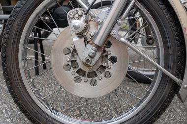 Gümüş kenarlı motosiklet lastiği. Çember motorun ön tekerleğine bağlı..