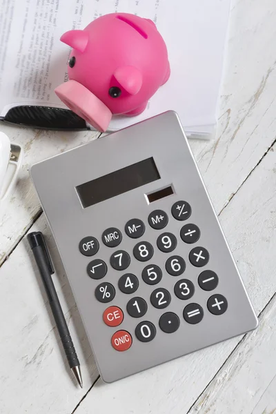 Kalkulator i piggy bank na biały drewniany stół — Zdjęcie stockowe