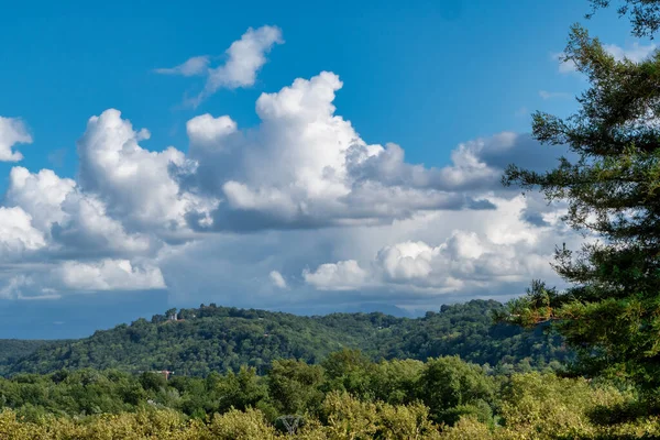 Ormanlı dağ manzarası, gökyüzü mavidir büyük beyaz bulutlarla.