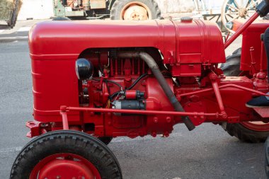 Siyah motorlu kırmızı traktör. Traktör caddeye park edilmiş.
