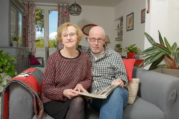 Eine Mutter und ihr erwachsener Sohn betrachten ein Fotoalbum auf einem Sofa — Stockfoto