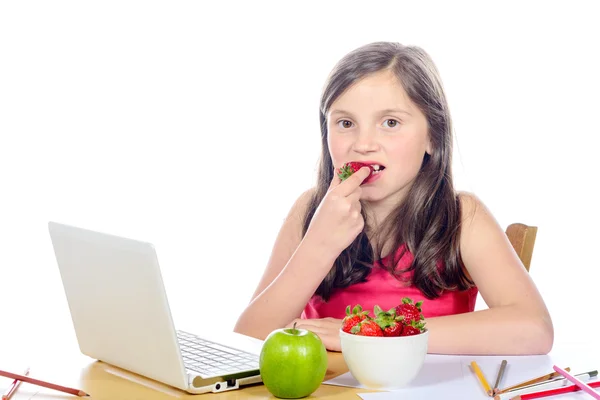 Mała dziewczynka jedzenie truskawek na biurku — Zdjęcie stockowe