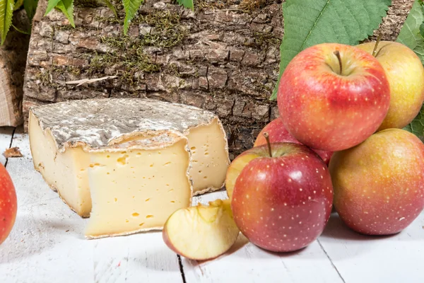 Käse mit mehreren Äpfeln auf einem weißen Holzbrett — Stockfoto