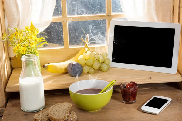 Colazione con latte, pane, tablet e telefono, sul bordo di un w — Foto Stock