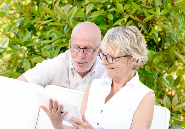 Pareja de mediana edad, sonriendo, usando una tableta en su jardín —  Fotos de Stock