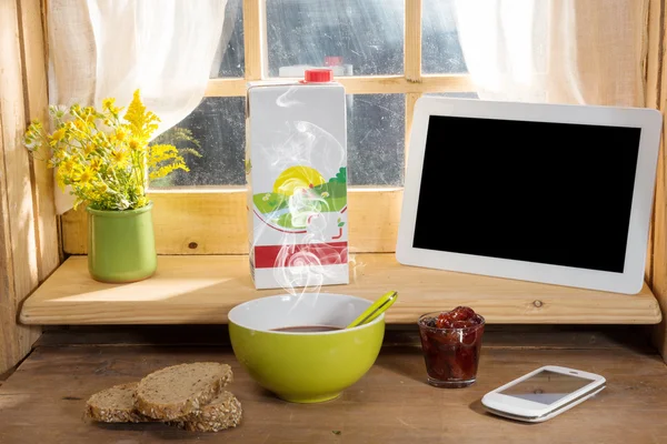 Frokost med melk, brød, nettbrett og telefon på kanten av en w – stockfoto