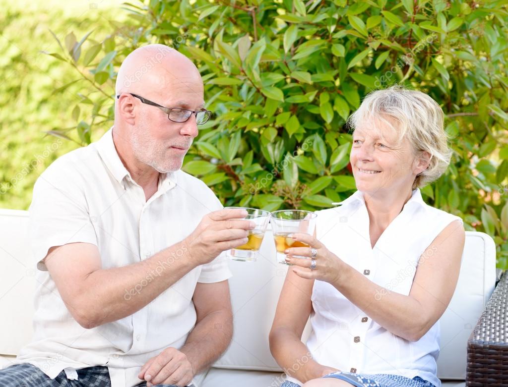 senior couple sitting in a sofa with a glass in hand