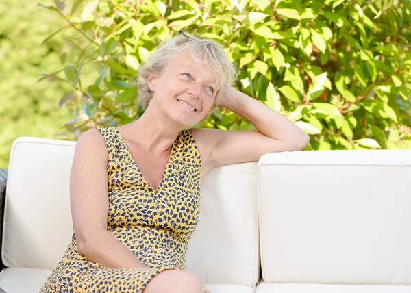 Donna bionda seduta sul divano, in un giardino — Foto Stock