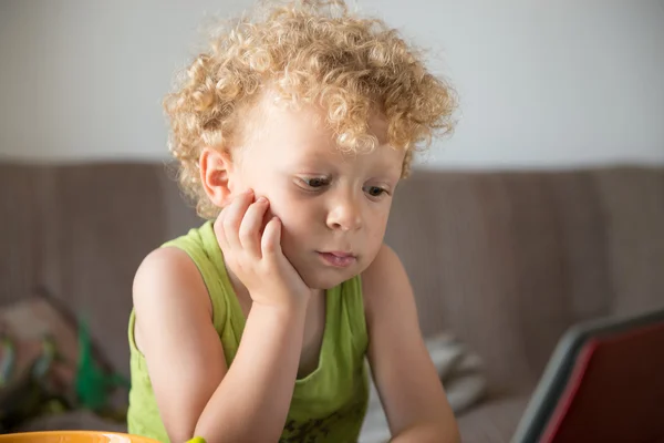 Jeune enfant blonde regarde une tablette — Photo
