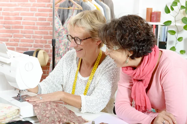 Deux femmes heureuses cousant dans leur atelier — Photo