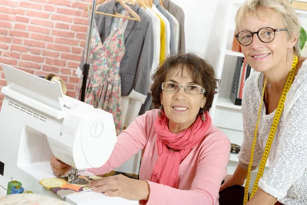 Zwei fröhliche Frauen, die in ihrer Werkstatt zusammenarbeiten — Stockfoto