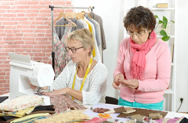 Zwei gut gelaunte Näherinnen arbeiten in ihrer Werkstatt zusammen — Stockfoto