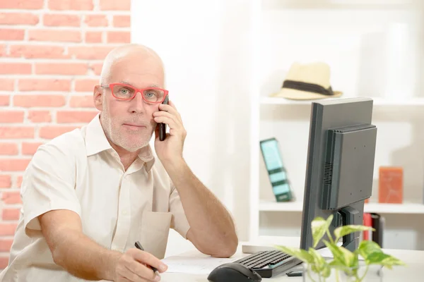 Middle Aged Businessman Sitting at Desk Talking on Cell Phone — Stock Photo, Image