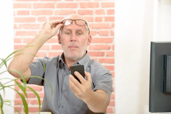 Mature man having trouble seeing phone screen because of vision problems — Stock Photo, Image