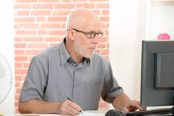 Homme d'affaires senior avec des lunettes rouges travaillant sur ordinateur — Photo