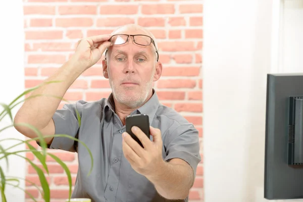 Зрелый человек не может видеть экран телефона из-за проблем со зрением — стоковое фото