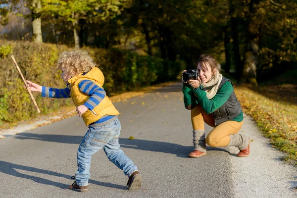 Веселая мать фотографирует своего милого маленького сына в парке , — стоковое фото