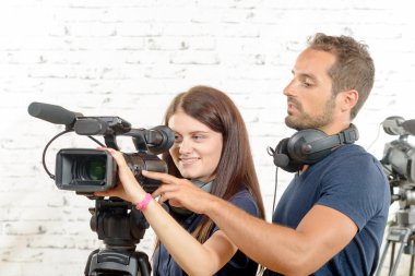 a young man and woman with professional video camera clipart