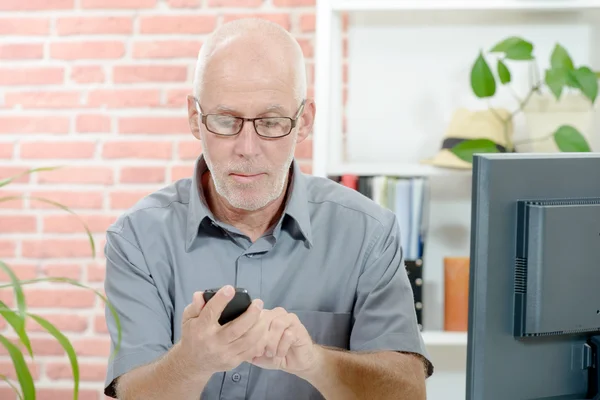 Midden leeftijd zakenman zit aan Bureau, met telefoon — Stockfoto