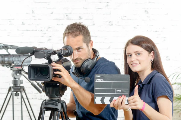 Un camarógrafo y una joven con una cámara de cine y aplausos — Foto de Stock