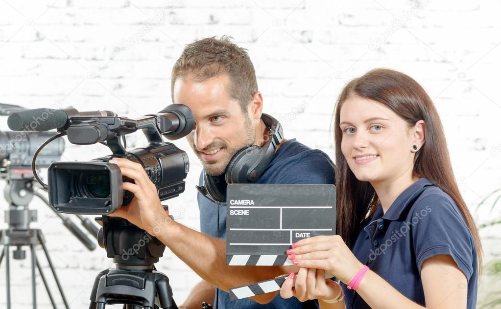 a cameraman and a young woman with a movie camera and clapper