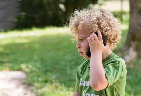 Bir cep telefonu ile oynarken küçük sarışın çocuk — Stok fotoğraf