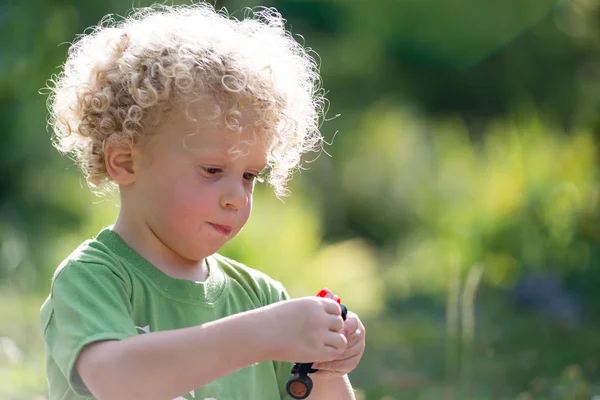 Liten blond pojke leker med en liten bil — Stockfoto