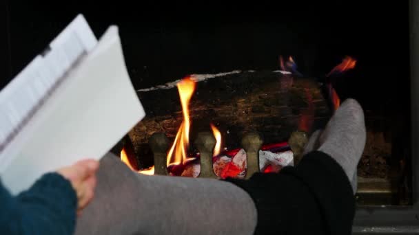 Μια γυναίκα διαβάζοντας ένα βιβλίο δίπλα στο τζάκι — Αρχείο Βίντεο