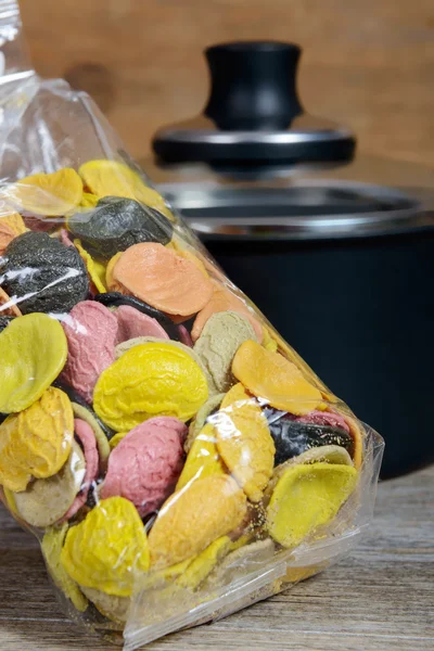 Sac de pâtes multicolores, une casserole en arrière-plan — Photo