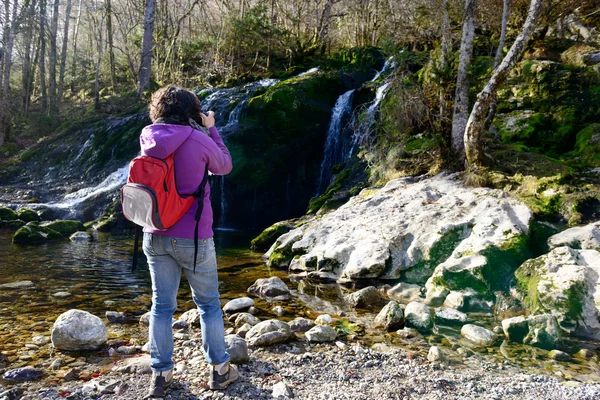 Женщина-фотограф фотографирует водопад осенью — стоковое фото