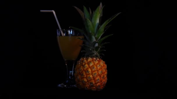 Ананасовый сок с фруктами на вращающемся черном фоне — стоковое видео