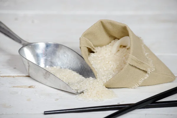 Rijst in kleine Hessiaan tas op houten tafel — Stockfoto